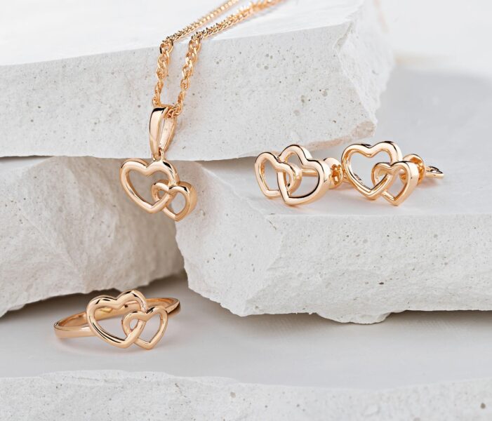 Jewellery set of hearts shape rose gold ring, pendant necklace and stud earrings on white background