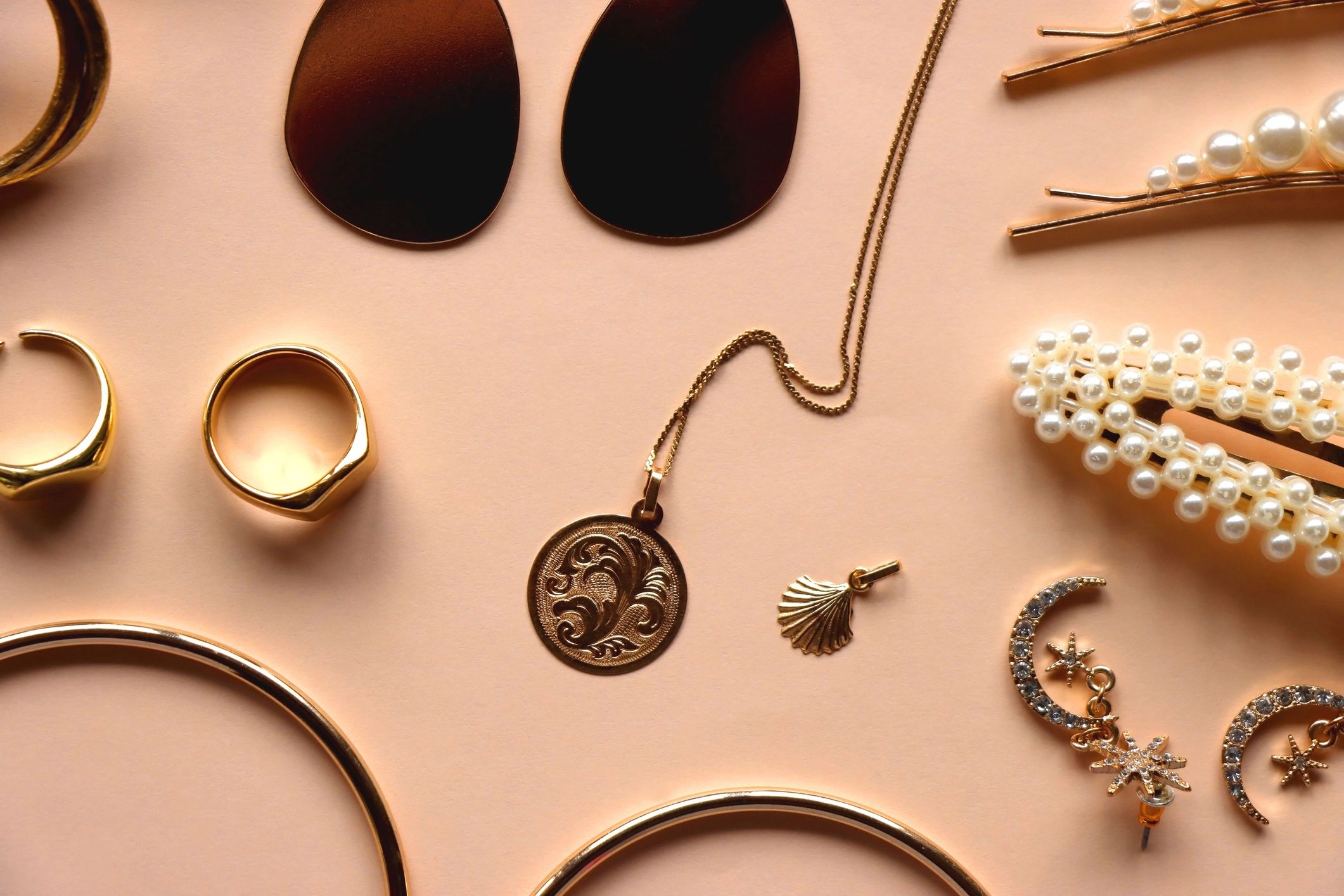 Gold jewelry flat lay on peach background