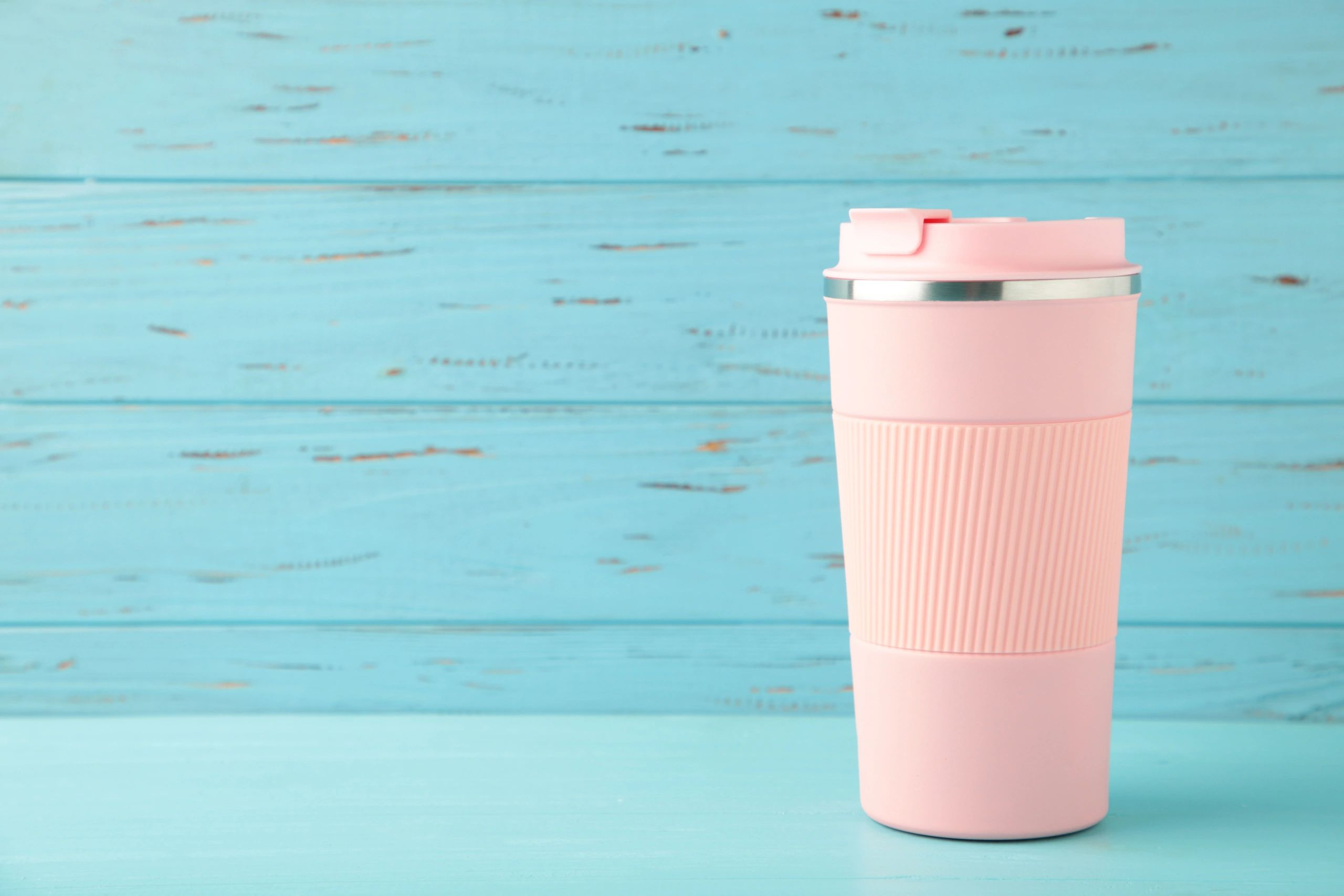 Pink thermo cup on blue background