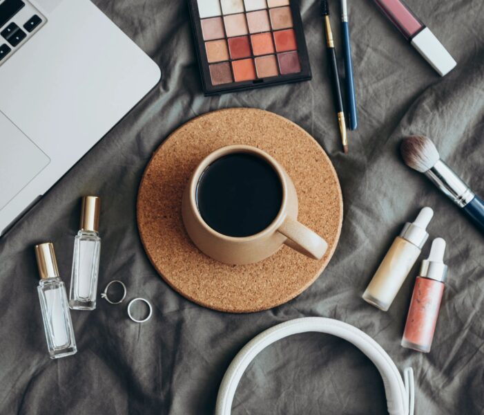 Woman fashion accessories, perfumes, jewelry and coffee on grey bed background.