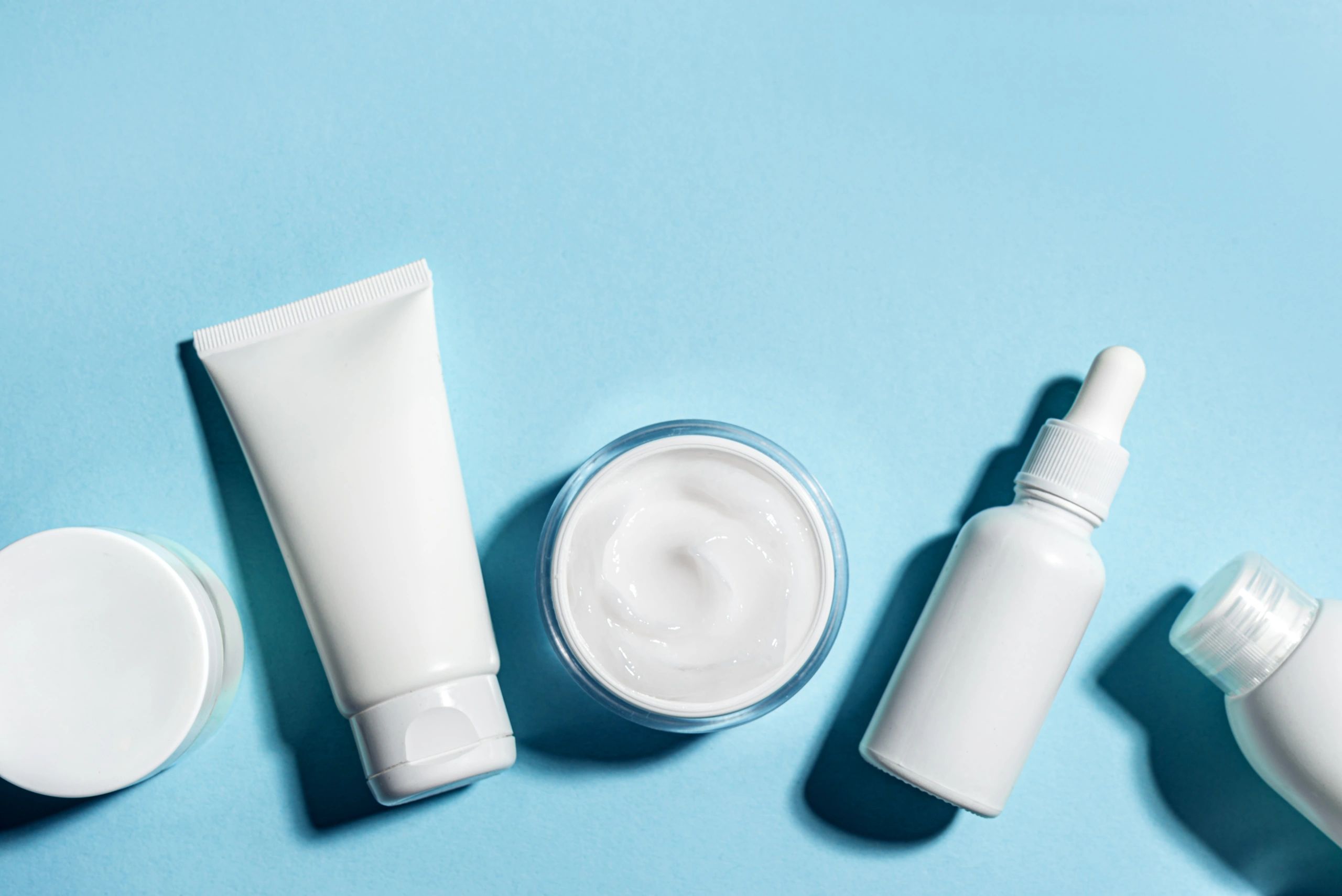 White cosmetic containers on blue background