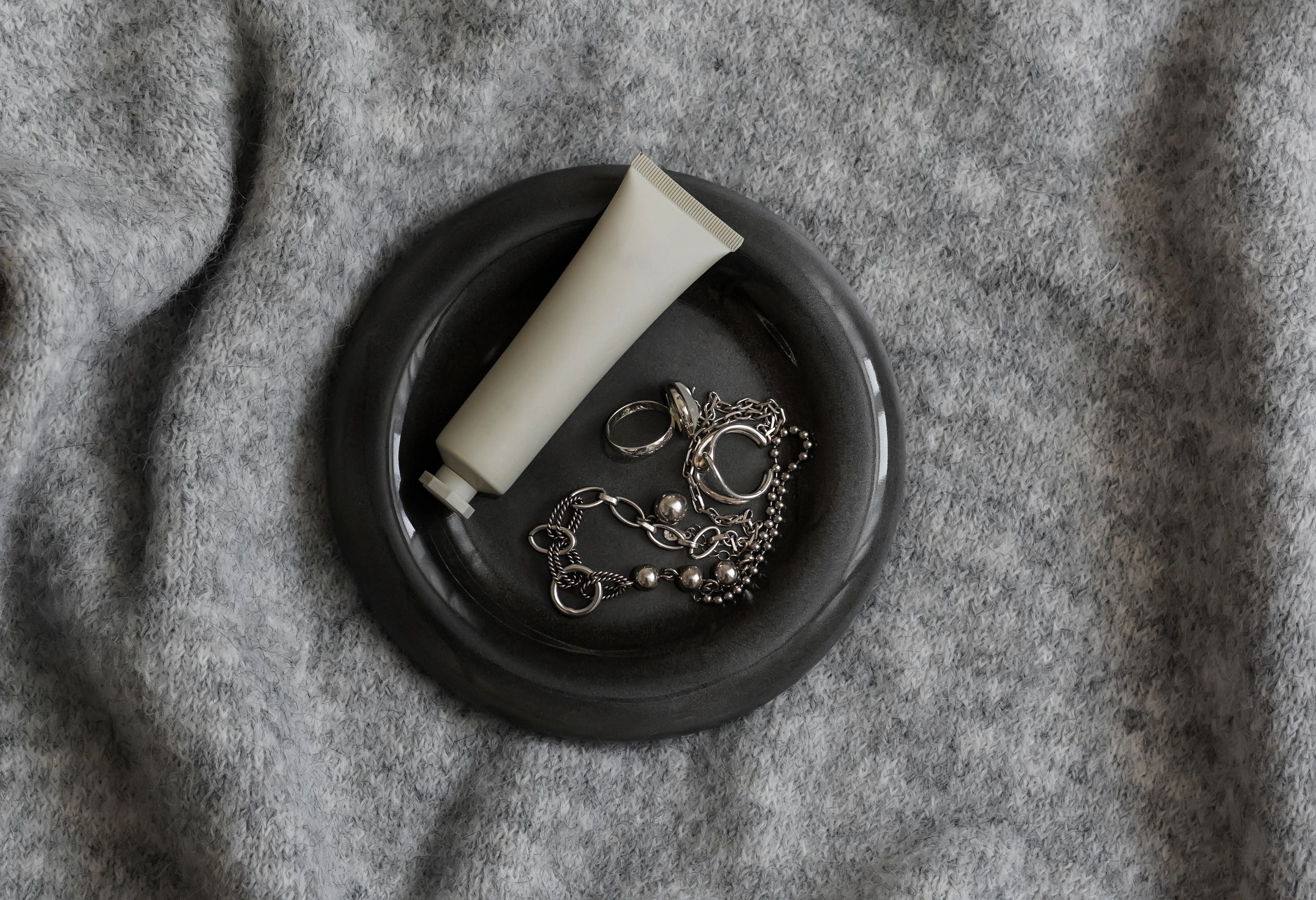 Cream and silver jewelry on ceramic plate