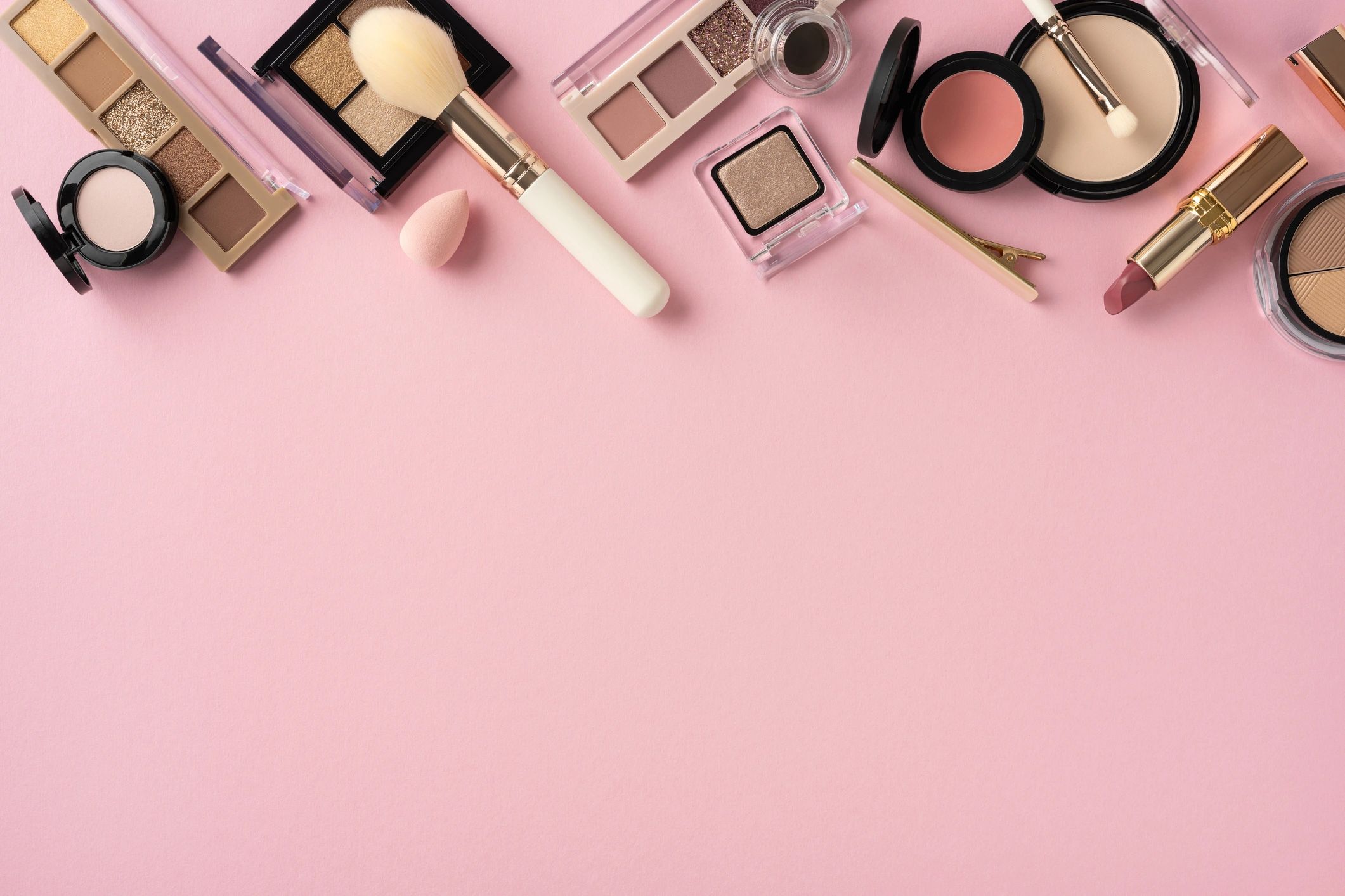 Makeup products flat lay on pink background