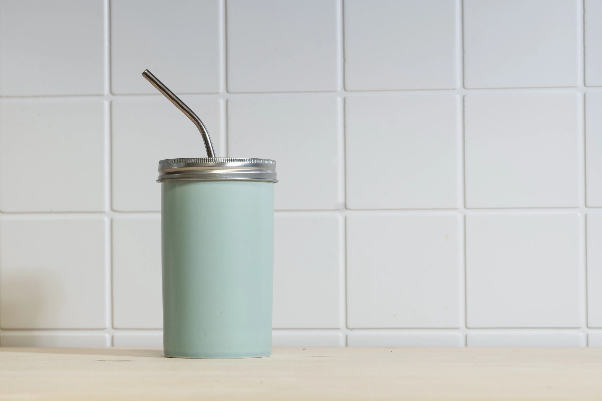 Reusable cup with metal straw on table