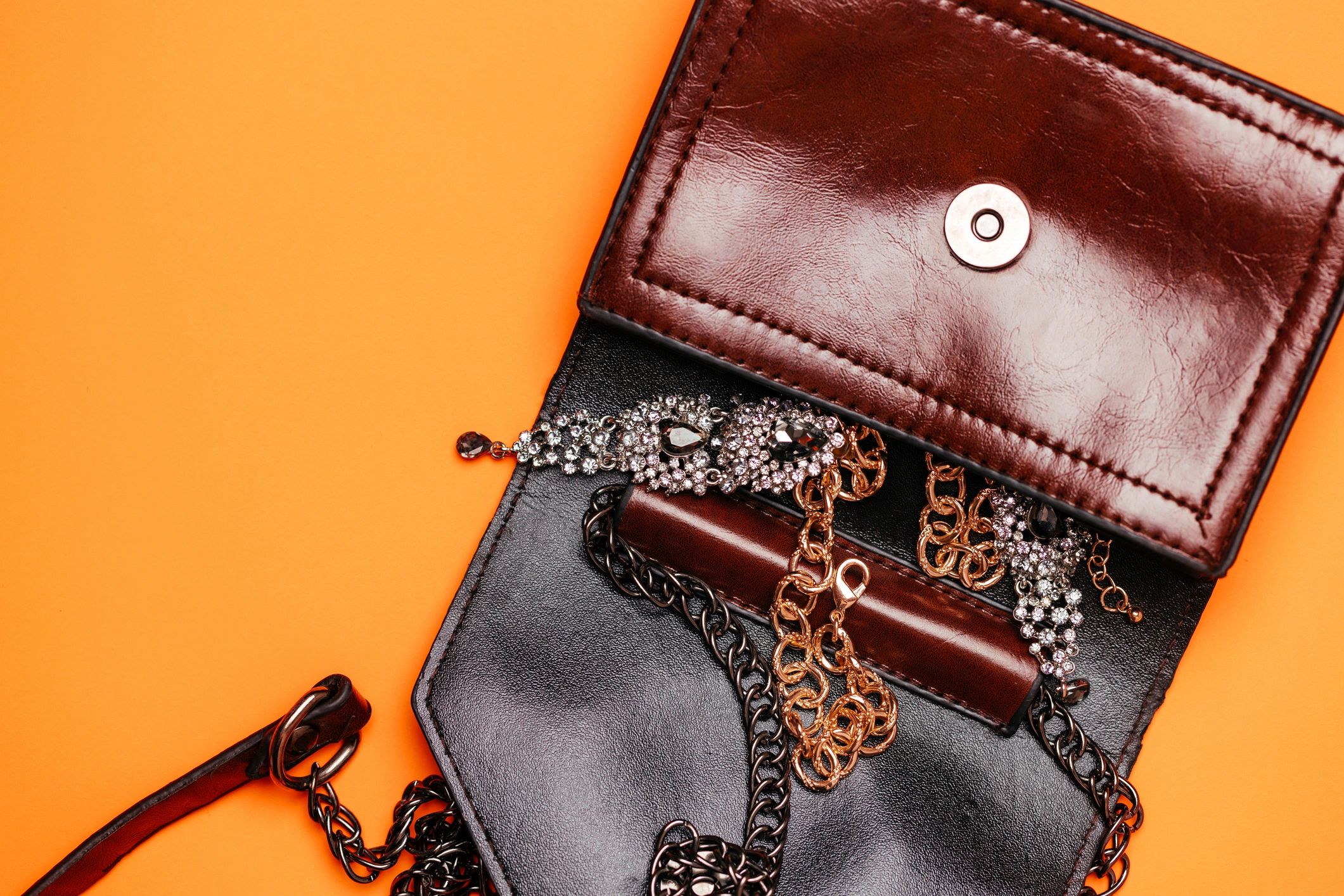 Handbag with jewelry on orange background